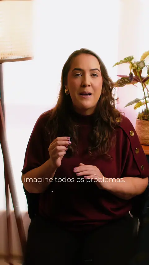 Clara Rocha fala para a câmera sentada numa sala clara com plantas
