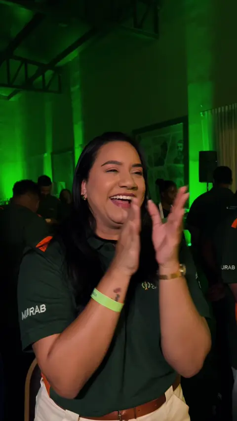 Participante do evento sorrindo e aplaudindo sob luz verde